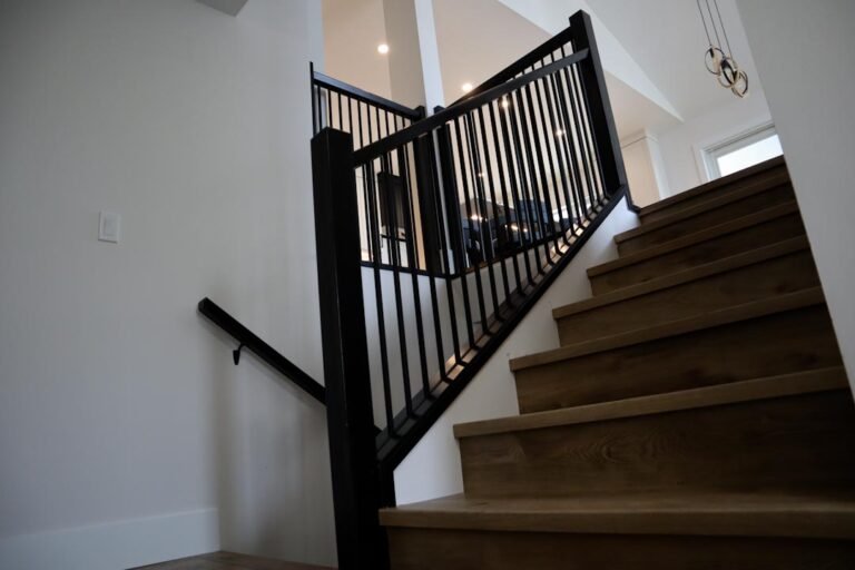 Custom modern staircase renovation in Cranbrook by Hand and Hammer featuring hardwood treads and a sleek black metal spindle railing.